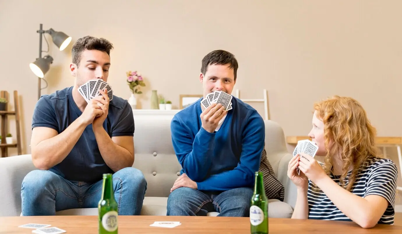 A group of friends at home playing cards and drinking beer.