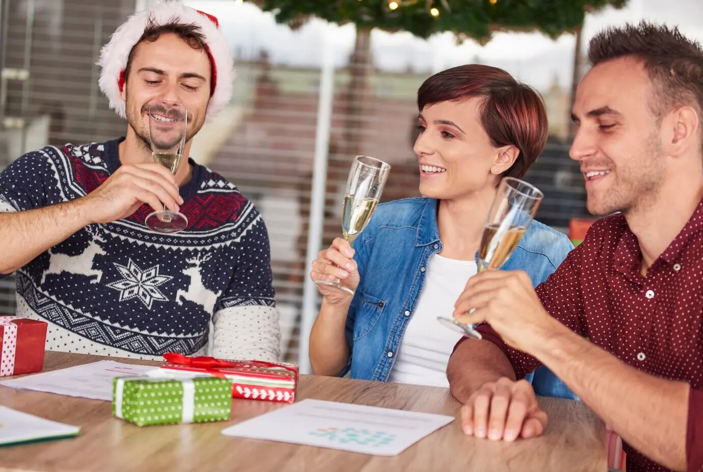 Three young people are drinking champagne at the office.
